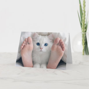 Cartão Gato de aniversário e pés humanos sob um edredão