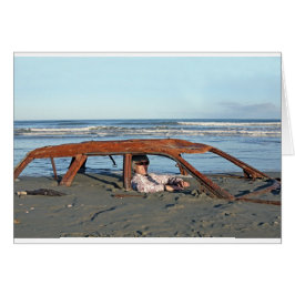 Cartão Homem sentado em um carro enferrujado na praia