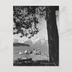 Cartão Postal Família tendo piquenique por montanhas do lago