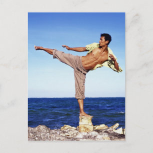 Cartão Postal Homem em artes marciais chutando posição, na praia