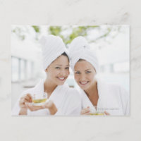 Mulheres nos bathrobes que bebem o chá em termas