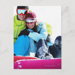 Cartão Postal Snowboarder couple sitting on snow