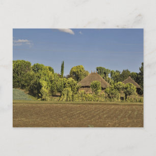 Cartão Postal Um campo agrícola em frente a casas com telhado de