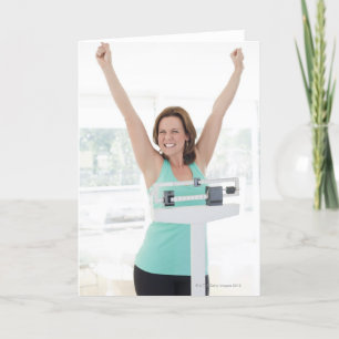 Cartão Successful weight loss. Happy woman weighing