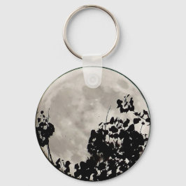 Chaveiro Lua atrás de folhas escuras