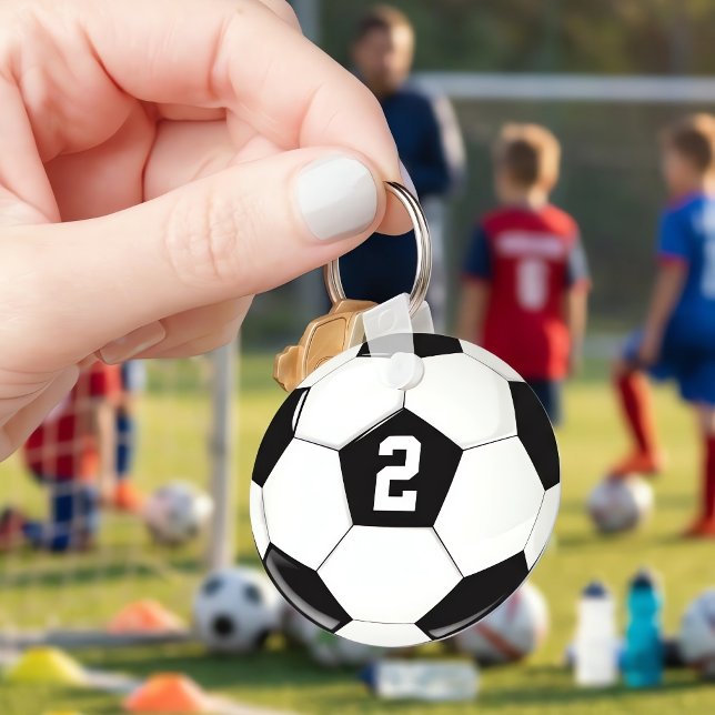 Chaveiro Número do Jogador de Futebol Personalizado da Bola (Holding a customizable soccer ball keychain at practice. Personalize with player jersey numbers.)