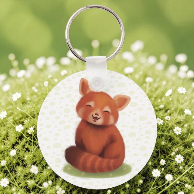 Chaveiro Panda Vermelho (A keychain with a hand-painted red panda, cute and smiling, laid on sunlit moss.)