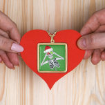 Colar Banhado A Ouro Feliz Ornamento De Esqueleto Pele Amarrou O Verde<br><div class="desc">Este colar tipo pingente tem um esqueleto de Natal feliz segurando dois ornamentos até seus olhos vestindo um chapéu vermelho de Papai Noel em um fundo verde com pequenos speck de ouro.</div>