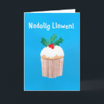 Cupcake do cartão de Natal (Galês) com azevinho<br><div class="desc">Um cartão de Natal brilhante e alegre de Galês com um sprig do azevinho sobre um cupcake congelado, de uma colagem de papel pintado à mão por Judy Adamson. O cumprimento dianteiro, no texto branco em um fundo azul, é "Nadolig Llawen!" e a mensagem interna, que você pode mudar, é,...</div>