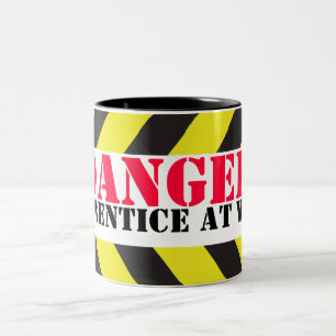 De Café Em Dois Tons Aprendiz do perigo na caneca dos trabalhadores da