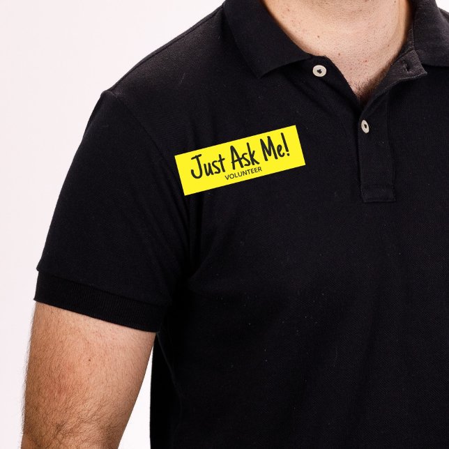 Etiqueta De Nome Voluntário Amarelo Me Peça Simples (Man wearing black shirt with yellow "just ask me" volunteer name tag badge.)