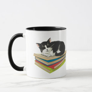 Gato dormindo na caneca de livros
