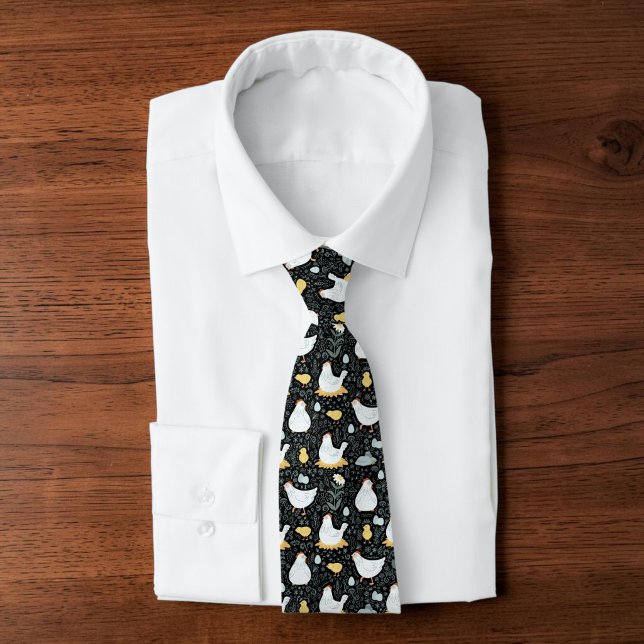 Gravata Pai de Galinha de Quintal Fazendeiro Excêntrico Ho (A black tie with a graphic chicken pattern design on it, atop a folded white collared shirt.)