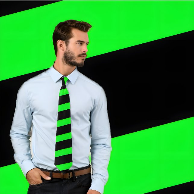 Gravata Torneiras Néon Verde e Negra (Espessuras) (Man wears neon green and black striped tie. He stands against green and black striped background.)