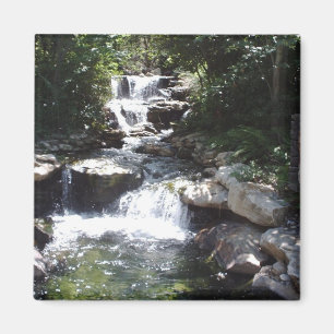 Íman A cachoeira flui sobre rochas na piscina calma