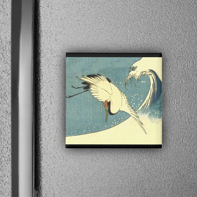 Íman Crane voando em uma onda (White crane bird flying over blue ocean wave black borders on magnet.)