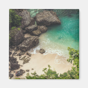 Íman Sandy Beach Cove com árvores verdes, rochas e oce