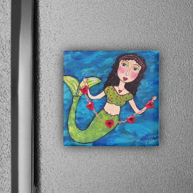 Íman Sereia Com Magneta De Corações (Mermaid green tail holding gold string of red heats on ocean blue magnet.)