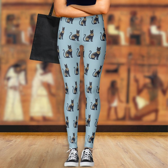 Legging Padrão de Gato Preto Egípcio Azul Empoeirado (A pair of light blue leggings with a pattern of Egyptian-style black and faux gold cats)
