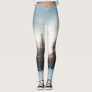 Legging Sol atrás de árvores de abeto