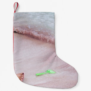 Meia De Natal Pequena Pé de pessoa ao lado da pá verde na costa