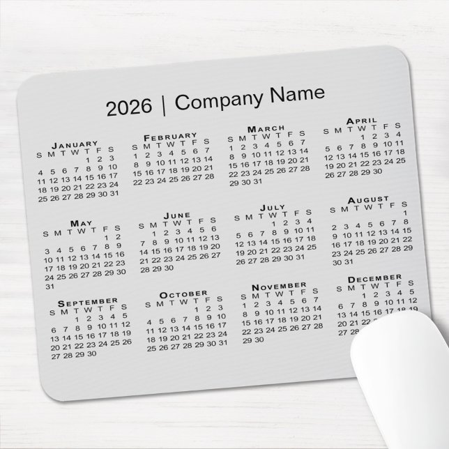 Mousepad Calendário Simples de 2026 com Nome da Empresa em  (Simple 2026 Calendar with Company Name on Grey Mouse Pad, in situ)