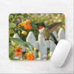 Mousepad Hummingbird with Touch-Me-Not Flower<br><div class="desc">A hummingbird,  its iridescent feathers shimmering in the sunlight,  hovers by a bright orange touch-me-not flower in a lush garden framed by a white picket fence</div>