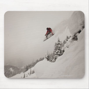 Mousepad Um snowboarder salta fora de um penhasco no pó