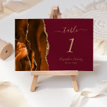 Numeração De Mesa Casamento Dourado Agate Burgundy, Laranja Queimado<br><div class="desc">Esta elegante e moderna placa de números da mesa de casamento apresenta uma cor de água laranja queimada,  borda agitada,  aparada com falso brilho dourado. O texto personalizável combina manuscrito dourado e fontes itálicas e em prato em fundo burgundy. Uma combinação de cores ideal para um casamento outono.</div>
