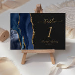 Numeração De Mesa Marinho Azul Dourado Agate Casamento Escuro<br><div class="desc">A borda esquerda desta elegante e moderna placa de número da mesa de casamento apresenta uma marinho azul de aquarela agata borda aparada com falso brilho dourado. O texto personalizável combina manuscritos dourados,  fontes itálicas e em placas em um plano de fundo off-black.</div>