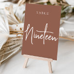 Numeração De Mesa Mesa NINETEEN com Script de Mão<br><div class="desc">Cartões simples e chic em tons de terra, marrom e branco, fazem uma declaração elegante no seu casamento ou evento. Design apresenta "mesa [number]" em uma combinação de olhares de serif clássica e de caracteres de script manuscritos. Design repete-se de ambos os lados. Cartões numerados individualmente vendidos separadamente; solicite cada...</div>