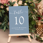 Numeração De Mesa Recepção de casamento Azul Dusty do Script Chic<br><div class="desc">Sinal de recepção de casamento azul empoeirado com "mesa" em um roteiro branco moderno de na moda com balanços, o número da tabela na elegante tipografia serif branca, seus primeiros nomes unidos por um coração e sua data de recepção. Crie cada número de tabela individualmente e adicione ao seu carrinho...</div>