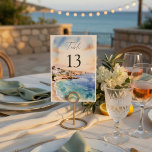 Numeração De Mesa Santorini Wedding Table Numbers | Mediterranean<br><div class="desc">Guide your guests in style with these elegant Santorini-inspired wedding table numbers, designed to complement a romantic Mediterranean destination wedding. Featuring a soft watercolor coastal scene with ocean blues and warm sunset tones, these table numbers add a refined and cohesive touch to your reception decor. The clean layout with bold...</div>