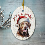 Ornamento De Cerâmica Chocolate Labrador Retriever Cachorro Joy para o M<br><div class="desc">Na frente deste ornamento de Feriado está uma bela imagem de um cão labrador de chocolate em um chapéu de Papai Noel. Atrás da imagem está um fundo de aspersão de confete dourado. O texto vermelho diz "Joy to the World". A parte de trás do ornamento tem o mesmo plano...</div>