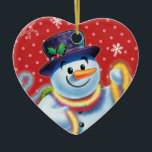 Ornamento De Cerâmica Condecoração de árvore de Natal cardíaca Snowman &<br><div class="desc">A forma cardíaca pica a decoração da árvore de Natal Snowman e tinsel.pinks. Esse bonitão está prestes a decorar sua árvore com uma casca colorida. Veja os outros caracteres nesta mesma série,  Papais noeis e Urso Polar e Rudolph.</div>