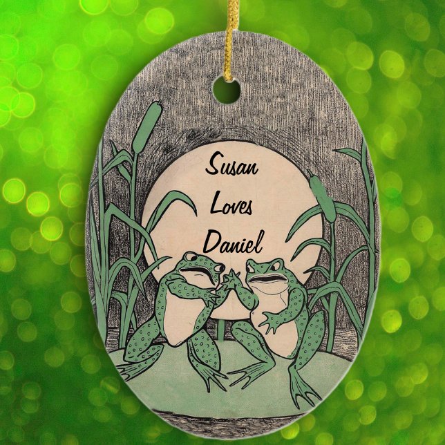 Ornamento De Cerâmica Divertido Argumento do Casal Verde na Lua Lily Pad (Cute green fighting frogs on lily pad full moon reed plants on black white oval hanging ornament.)