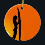 Ornamento De Cerâmica Surfista Sunset Girl com surfboard<br><div class="desc">Uma legal design de uma silhueta de uma surfista segurando seu surfboard contra um pôr de sol laranja brilhante. Esta praia,  a design de inspiração de Summer é brilhante e vibrante e para amantes do surfe e do estilo de vida na praia em todo o mundo.</div>