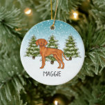 Ornamento De Cerâmica Vizsla Dog Snowy Winter Forest E Nome Húngaro<br><div class="desc">A ilustração original de um bonito cão da raça Vizsla Húngara, de Destei. O cão é colocado numa cena de inverno com três árvores de abeto verde e neve caindo. O fundo é um gradiente azul a branco que dá à design aquele olhar frio do dia de inverno. Há também...</div>