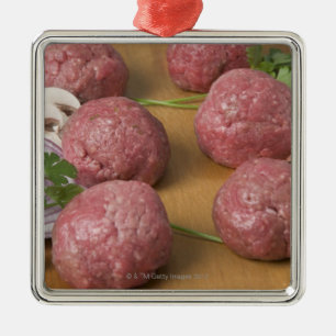 Ornamento De Metal Meatballs crus em um conselho de corte