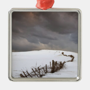 Ornamento De Metal Uma cerca quebrada ao longo de um campo coberto de