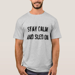 "Permaneça a calma e o trenó" no t-shirt cinzent