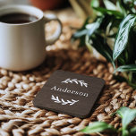 Porta-copo Rústica Castanha Escura Madeira Laurel Sobrenome M<br><div class="desc">Esta elegante e personalizada montanha-russa monificada apresenta galhos de louros de folha que moldam um sobrenome da família. Um belo presente para recém-casados ou novos proprietários. Um fundo de grãos de madeira escura castanho-noz adiciona um olhar rústico texturizado ao design. O texto de serif branco clássico pode ser modificado via...</div>