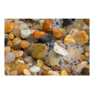 Póster Muitas rochas caídas numa praia arenosa com água