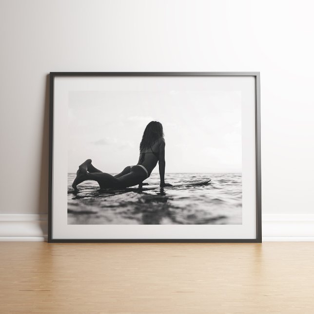 Poster Surfista Negra e Branca no Oceano (Black and White Surfer Girl in the Ocean Poster on floor in black frame)