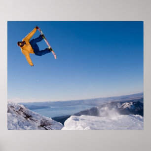 Póster Um praticante de snowboard gira fora de um salto n