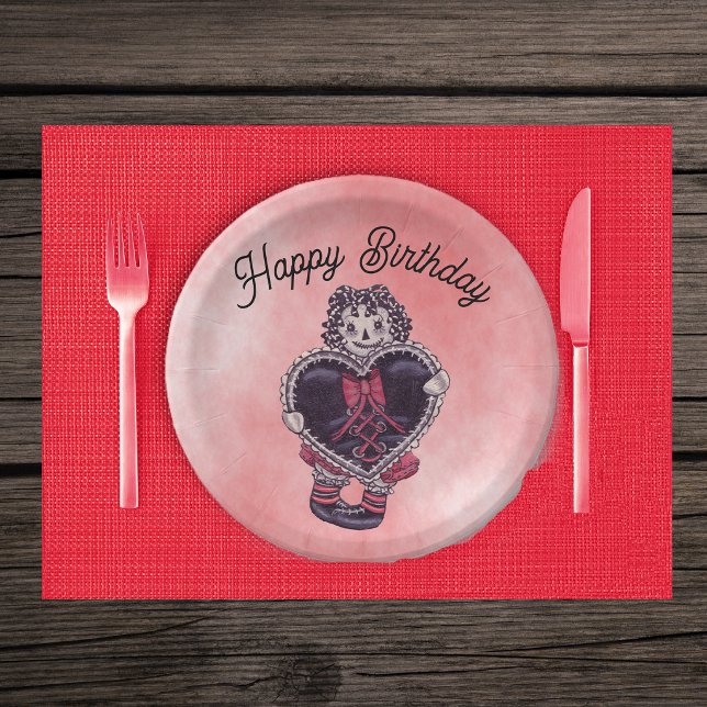 Prato De Papel Boneca de Trapo Gótica Preta com Laço Vermelho Ani (Smiling Gothic rag doll yarn hair with black lace trimmed heart and bow on pink paper party plates.)