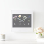 Relógio Quadrado LOVE Floral  – Impressão Botânica Romântica<br><div class="desc">Adicione um toque de elegância e calor à sua casa com este belo relógio de parede com tipografia floral LOVE, apresentando quatro flores delicadas dispostas acima de letras brancas limpas em um painel moderno cinza-escuro. A suave obra de arte botânica combinada com o layout minimalista torna este relógio uma adição...</div>