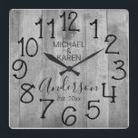 Relógio Quadrado Nome da Família Personalizada da Casa Farmônica de<br><div class="desc">Um design rústico, único, personalizado, de um tipo, apresenta um fundo de madeira falsa com as palavras "MICHAEL & KAREN Anderson est. 20XX" em tipografia negra. Personalize este relógio adicionando suas próprias informações pessoais. Faz um casamento excelente, aniversário ou presente de inauguração. Clique em "personalizar este modelo" para alterar os...</div>