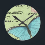 Relógio Redondo Borboleta de asa azul no cartão postal<br><div class="desc">Este cartão-postal teal carregar uma mensagem de beleza. Uma delicada borboleta de asas azuis repousa no cartão,  ocultando alguns dos escritos que contém. Este impressão do Vision Studio faria uma adição de excelente à sua casa!</div>