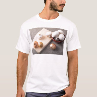 T-shirt Cogumelos e cebolas crus do cogumelo na mesa